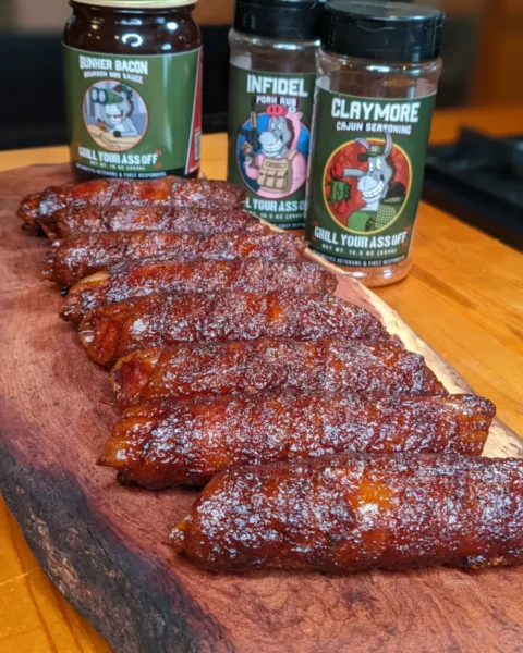 Bacon-wrapped shotgun shells glazed and sliced on a cutting board